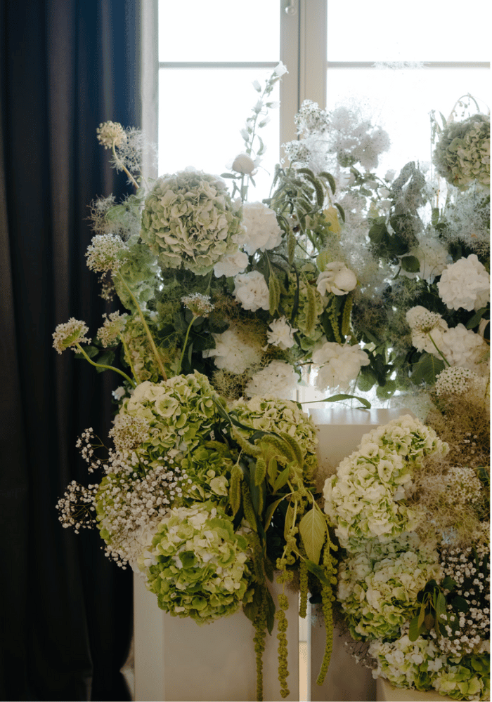 composition florale de mariage gigantesque, mélange de tons blanc et de vert, sur colonnes